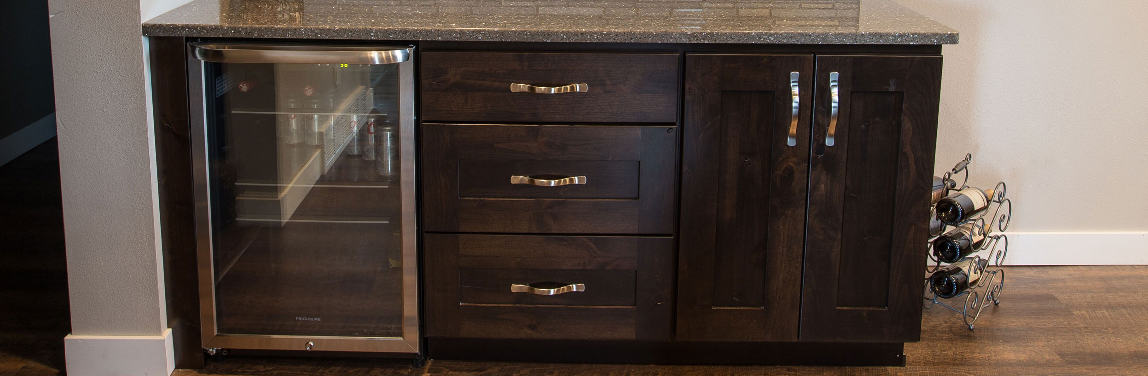 Custom built-in mini bar with espresso colored cabinets, stone countertop, and wine cooler